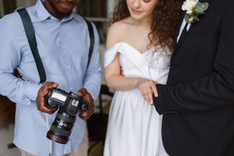 fotografo especializado en fotografia para eventos enseñando las fotos que tomo a una pareja de recien casados en Puebla