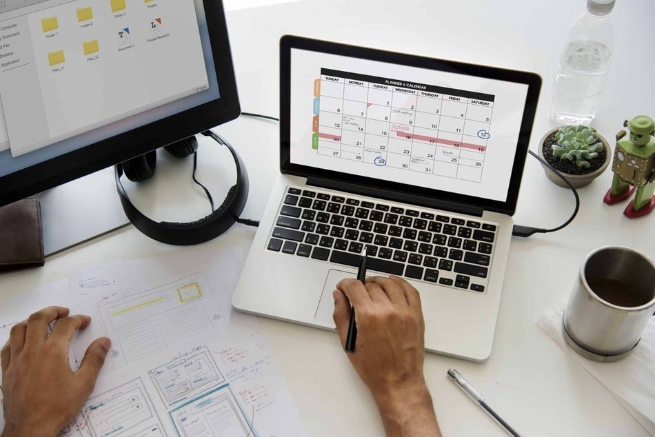 fotografia de una computadora sobre un escritorio con un calendario ejemplificando un servicio de gestion de redes sociales
