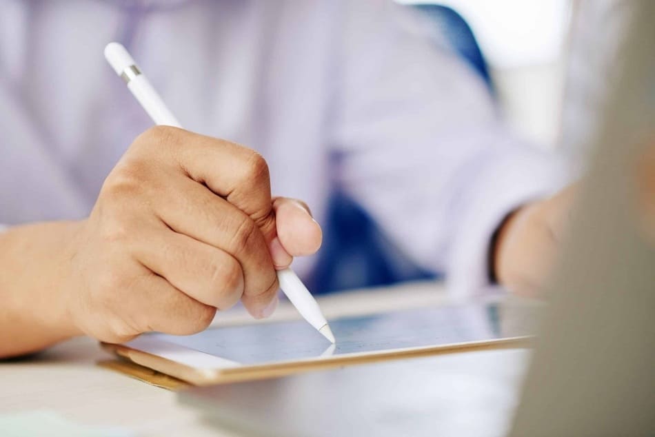 primer plano con enfoque en la mano de una persona firmando un contrato digital en una tableta con respecto a un servicio fotografico en Puebla