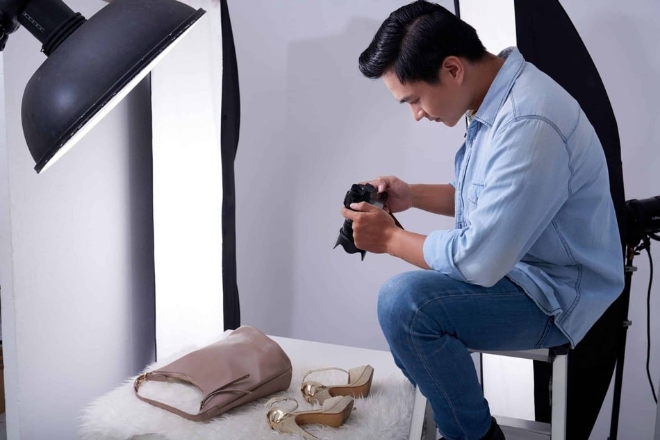 hombre fotografo en un estudio de fotografia en Puebla realizando una sesion a un bolso y par de zapatillas