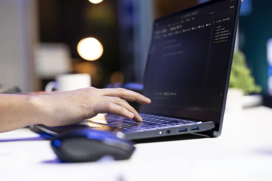 Programador escribiendo código en laptop dentro de una agencia de diseño de páginas web en Cholula y Puebla.