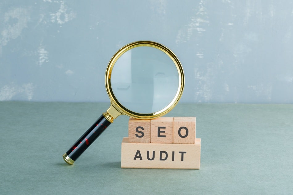 lupa con bloques de madera que juntos dicen "auditoria seo" ejemplificando el trabajo de una agencia seo en Puebla